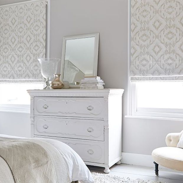 cream roman blinds in a bedroom with 2 windows