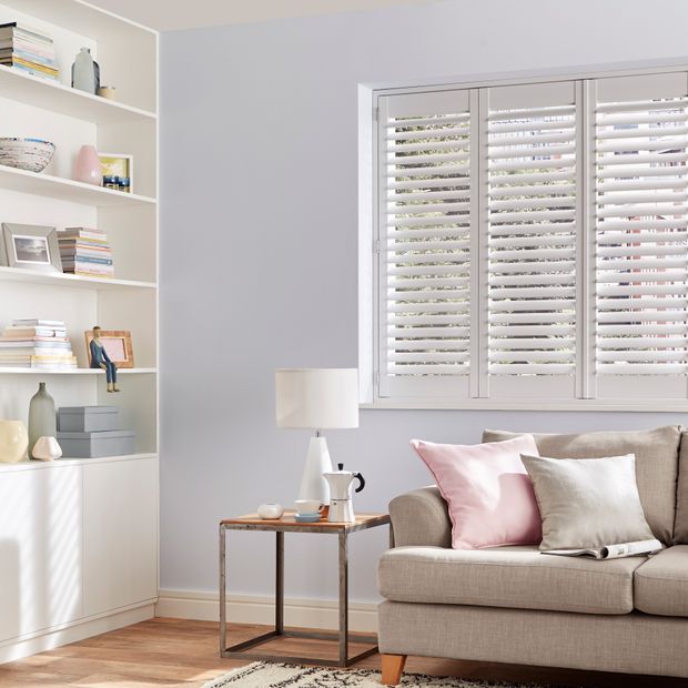 White tracked shutters fitted to a window in a living room