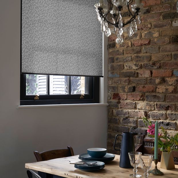 Rustic dining room with exposed brick wall and a grey pattern roller blind