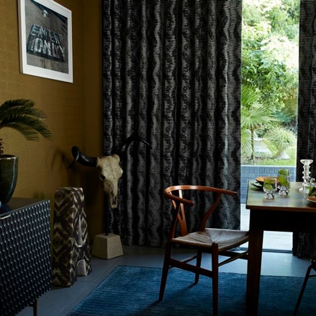 Black and white styled curtains hanging from a door window in a dining room with a wooden table and chairs