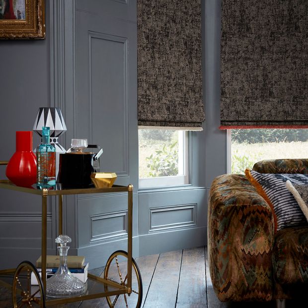 Modern gothic living room with gold serving trolley and dark grey pattern roman blinds in a victorian bay window