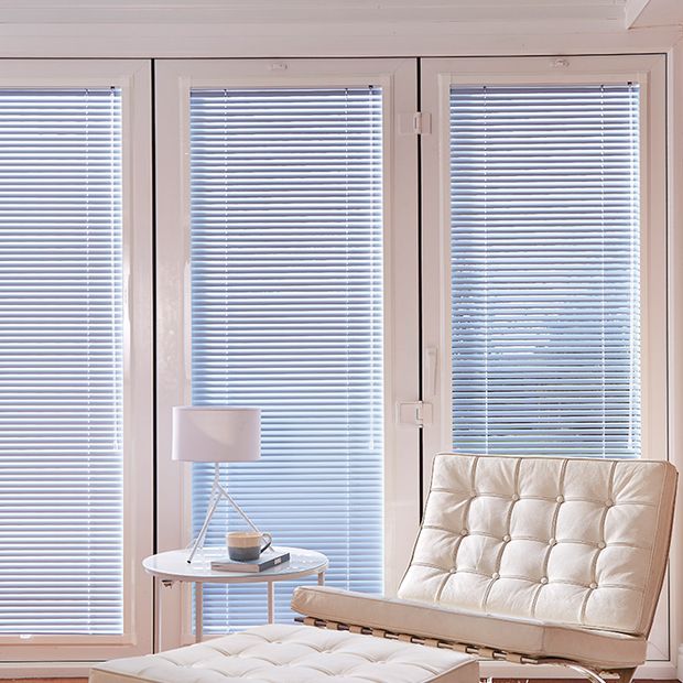 Living room lounge chair next to bifold doors with blue perfect blinds