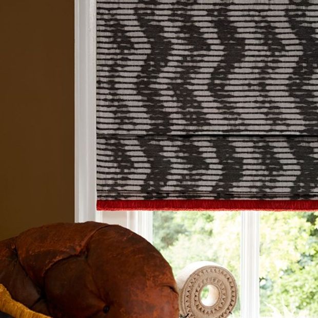 Sofa next to window covered by Cadillac Noir Roman blinds with Colette Vixen fringing
