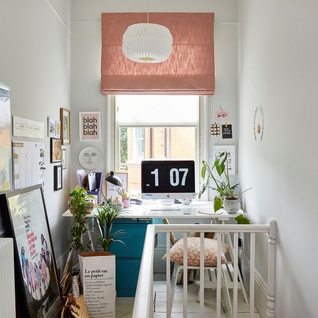A white office space situated at the top of a staircase, with a pink blind in the window