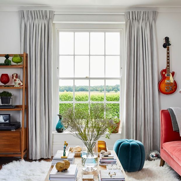 Living room with sash window and full length cream curtains