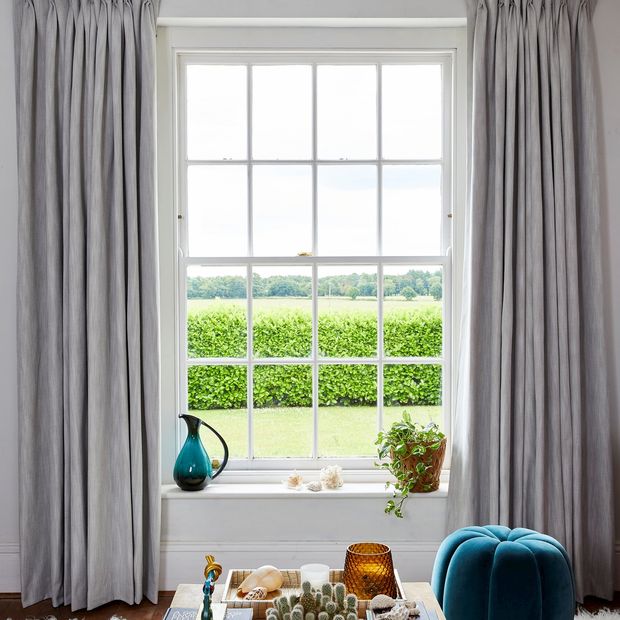 A single sash window dressed with light grey curtains