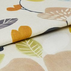 White fabric decorated with floral patterns in a variety of colours including green, pink and orange