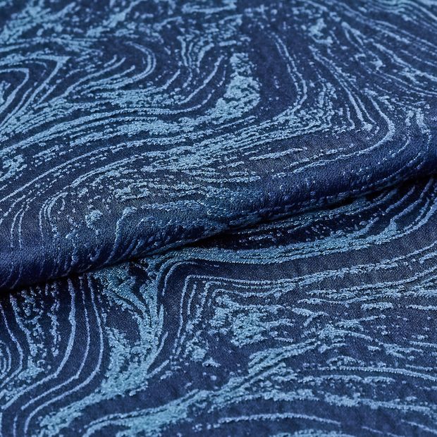 A repeating swirling pattern made up of dark and light blue on the material