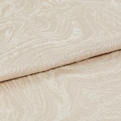 Cream and white coloured fabric in a repeating swirling pattern