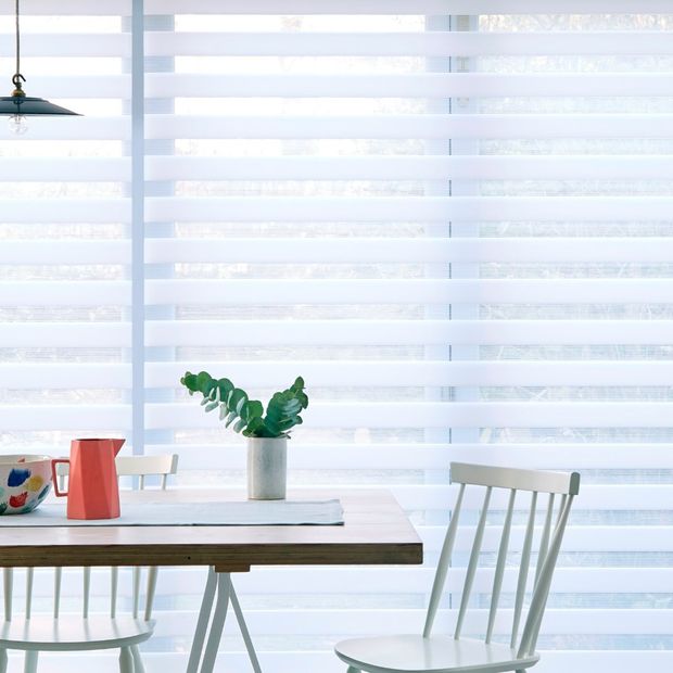 A close up of a white Day & Night blind in a kitchen with a table