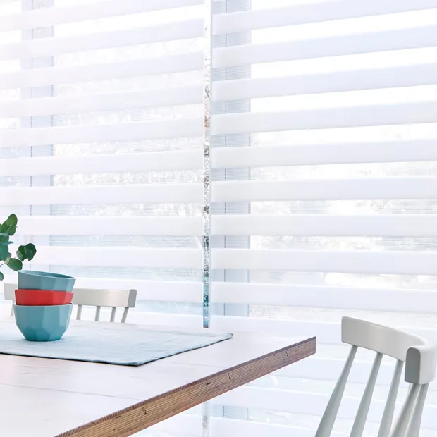 A close up of a white Day & Night blind in a kitchen with a table