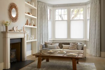 White curtains featuring light grey pattern on curtains dressed over cafe style Pleated blinds on windows of living room.