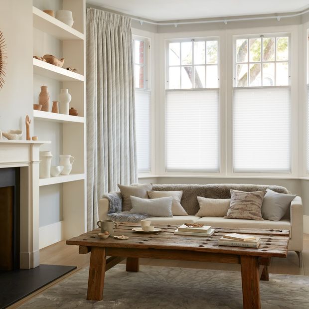 White curtains featuring light grey pattern on curtains dressed over cafe style Pleated blinds on windows of living room.