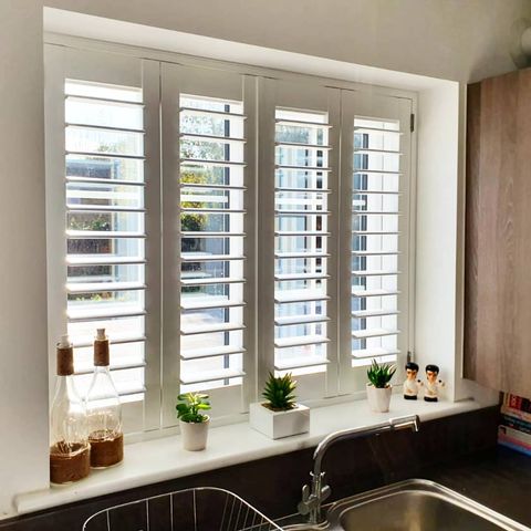 white shutters installed on a kitchen window above a sink