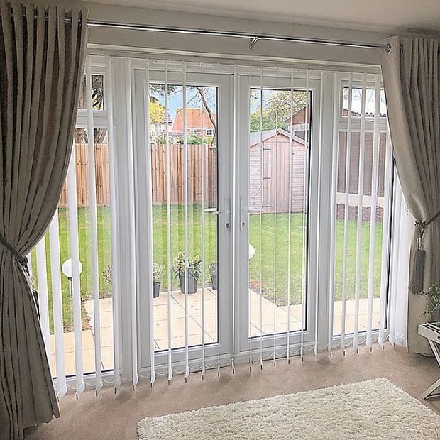 White verticals under beige curtains hanging on patio doors