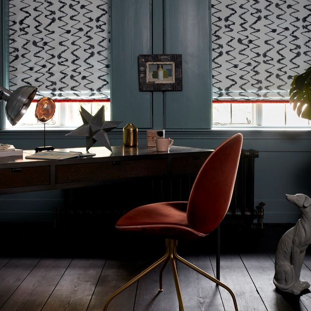 Black and white styled Abigail Ahern roman blinds with a zig zag pattern fitted to rectangular windows in a study with blue walls