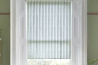 green striped roller blind in white window on a green wall