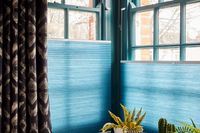 teal pleated blind coming from bottom up on dark windows in corner of room
