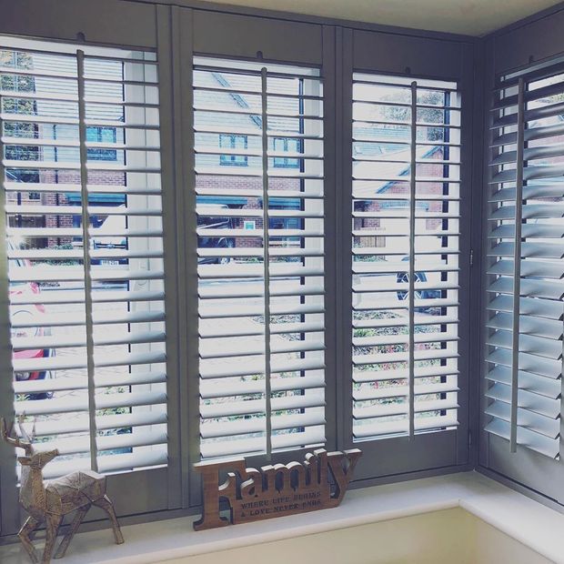 Storm grey shutters fitted in box window with wooden family windowsill ornament