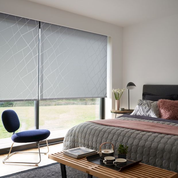 roller blinds in zimmer silver fitted to tall windows in a bedroom
