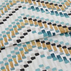 A folded piece of fabric with Holi Aquarelle Teal printed on it