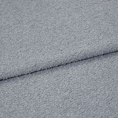 A folded piece of fabric with Soho Bouclé Cornflower Grey printed on it