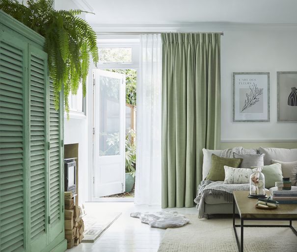 Pearl olive green floor length pinch pleat curtains paired with voiles in cosy living room