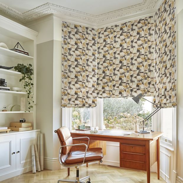 Fraction amber geometric roman blinds on bay window in home office