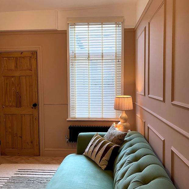 White faux wood venetian blinds with pearl tape in green living room