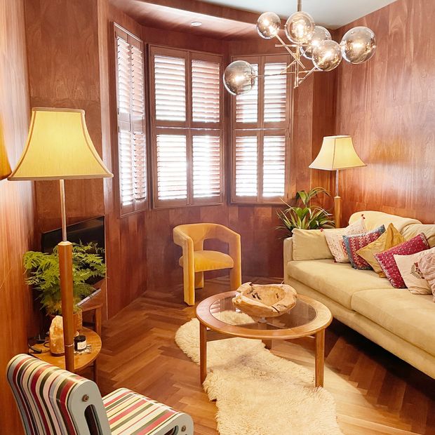 tier on tier taupe wooden shutters on bay window in retro lounge