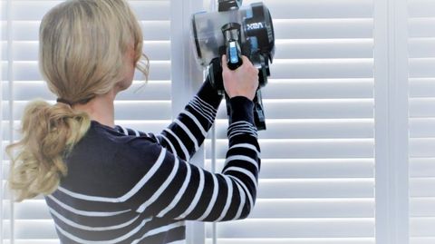 woman cleaning shutters with vacuum