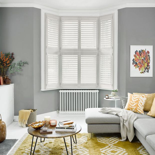 matte white tier on tier shutters on bay window in living room