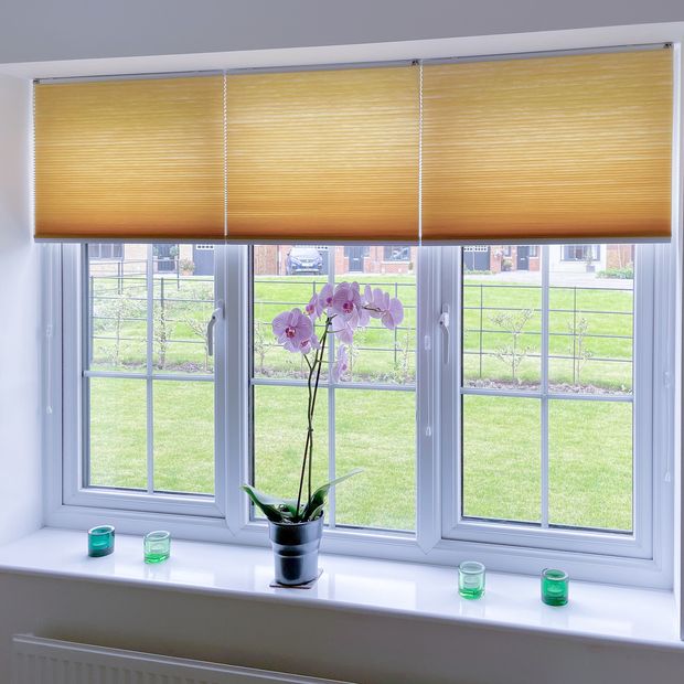 orangey brown half open pleated blinds on window with minimalist decor