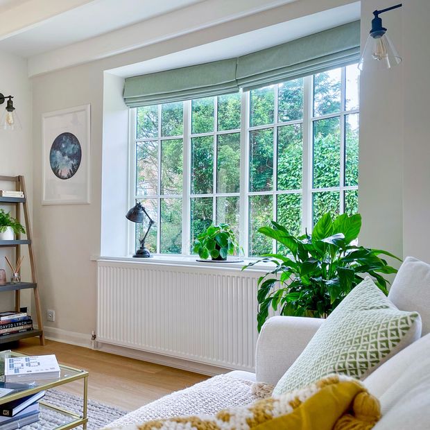 pair of light turquoise roman blinds in cosy living room with greenery, blankets and rugs