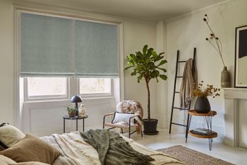 Bedroom in smoky beige tones with two steel blue Roman blinds at the window.