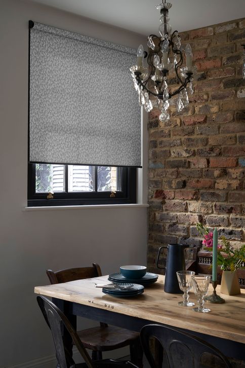 Rustic dining room with exposed brick wall and a grey pattern roller blind 
