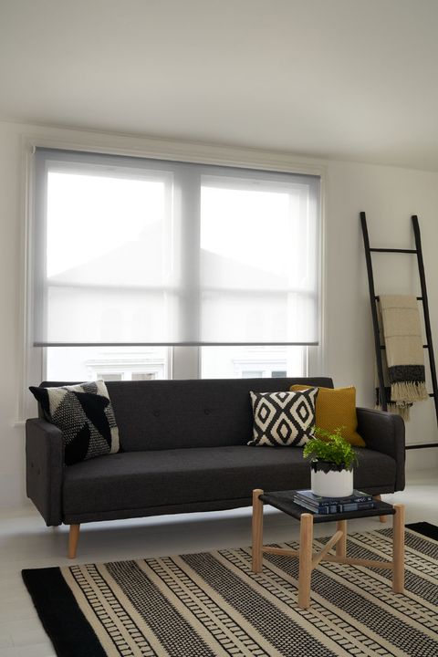 Modern minimalist living room with dark grey sofa and window dressed with voile roller blinds 