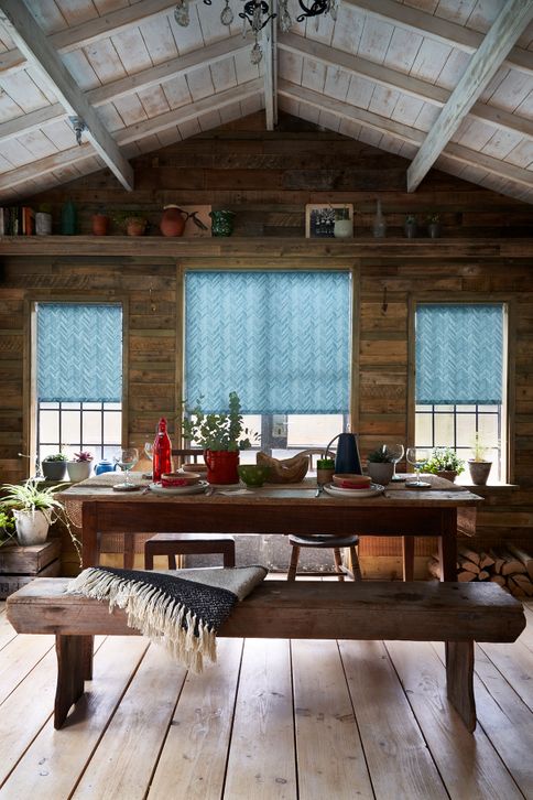 Rusitc log cabin dining room with scandi design and windows dressed with blue roller blinds