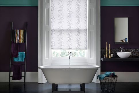 Modern bathroom with dark purple walls and a patterned white roller blind