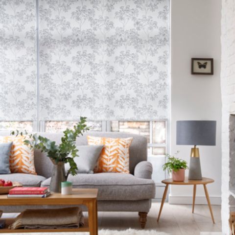 Grey couch in a living room in front a large window fitted with Elona Silver Roller blinds