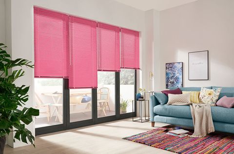 A white room featuring bi-fold doors that have individual bright pink Venetian blinds 