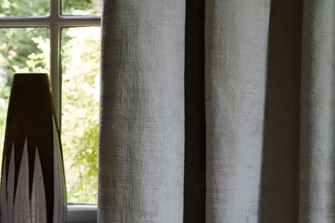 Close up detail of grey textured velvet curtains and black and white vase