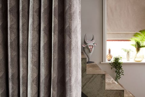 Artistic close up of snakeskin print velvet curtain with concrete stairs behind