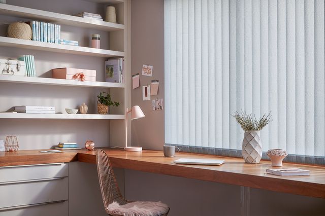 Off-white Vertical blinds in a home office. The blinds are above an oak desk