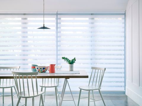 Dining room table with wide windows in the background with day and night roller blinds