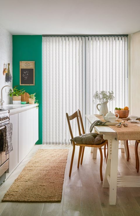 Modern kitchen diner with statement green walls and full length window with patterned vertical blinds