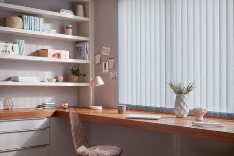 Modern home office with build in desk and shelves and windows dressed with pale blue vertical blinds