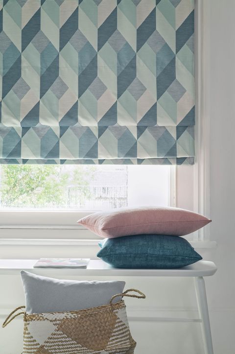close up of blue Roman blinds in white bedroom with a window that has cushions in front of it