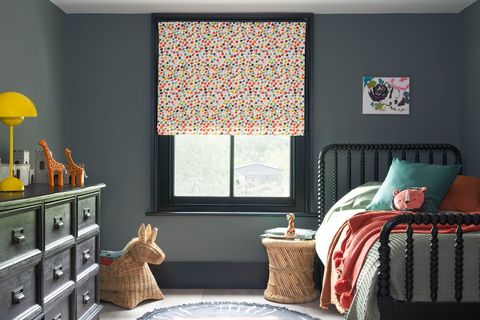 A grey children's bedroom with multi-coloured dotty Roman blinds