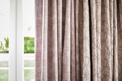 close up of neutral beige featuring delicate embroidery curtains and  textured shimmering purple curtains hanging on doors